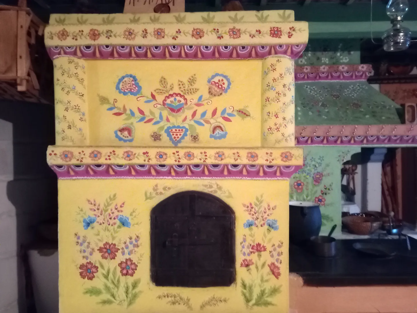 Traditional Polish stove with colorful floral folk art, showcasing vibrant yellow, purple, and green patterns